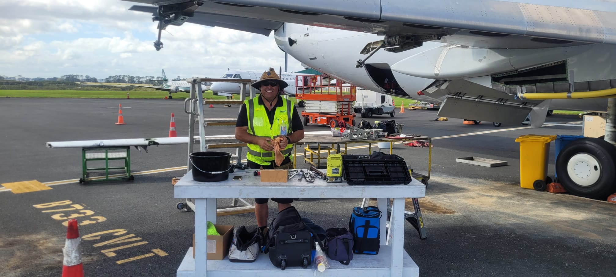 Aircraft engineer performing on-site maintenance support beneath aircraft wing